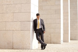 Sad businessman next to some wall looking down