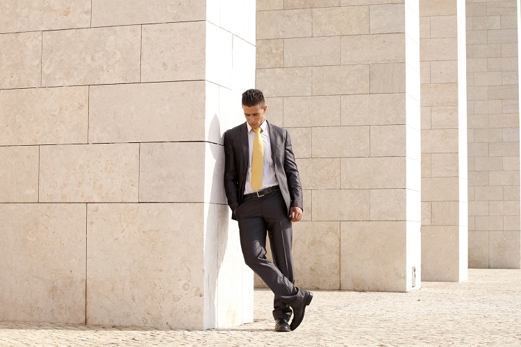 Sad businessman next to some wall looking down