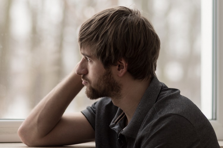 man Sitting at the window batteling Eating Disorders and Addiction