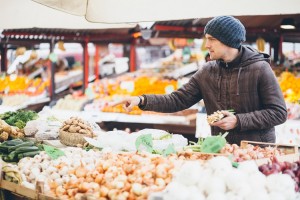 Young man buying fresh vegetables at farmer's market