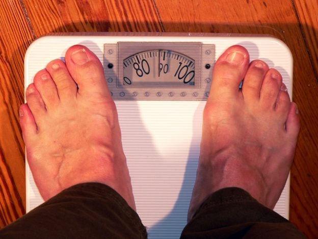 Man Concerned about His Weight Standing On A Weight Scale
