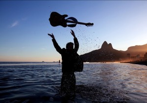 Man who overcame Substance Abuse standing in water throwing up a guitar