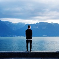 Man at lake edge gazing at mountain