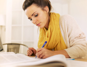 Studious woman doing her research at home and writing something