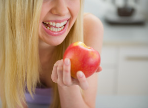 Closeup on smiling teenager girl eating apple