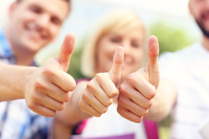 A picture of a group of students showing ok signs in the park