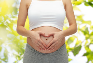 close up of pregnant woman touching her bare tummy