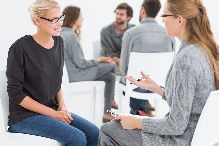 Group therapy session with therapist and client in foreground