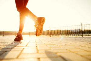 Runner feet running on road closeup on shoe. woman fitness sunri