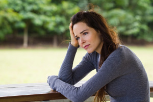 Sad depressed woman sitting outdoors after drinking Alcohol