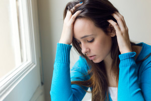 Depressed young woman sitting at home.