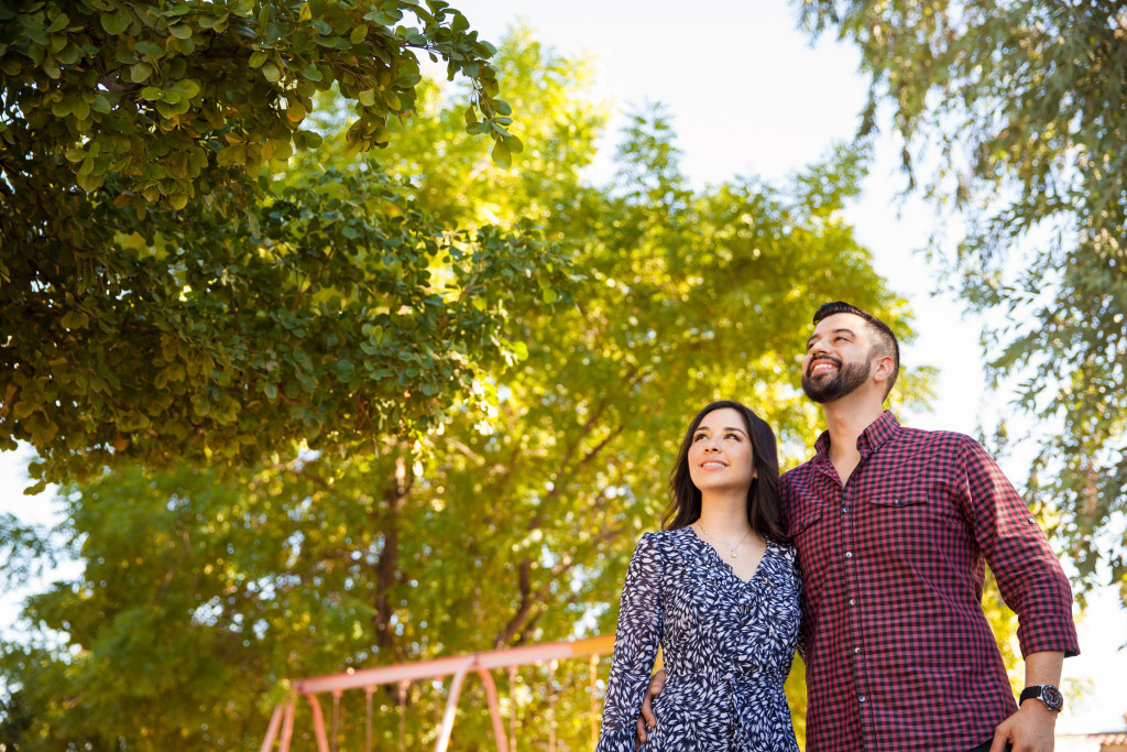 Portrait of a young couple hanging out at a park and looking up towards copy space