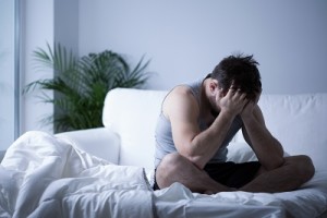 Young man having depression sitting on the bed