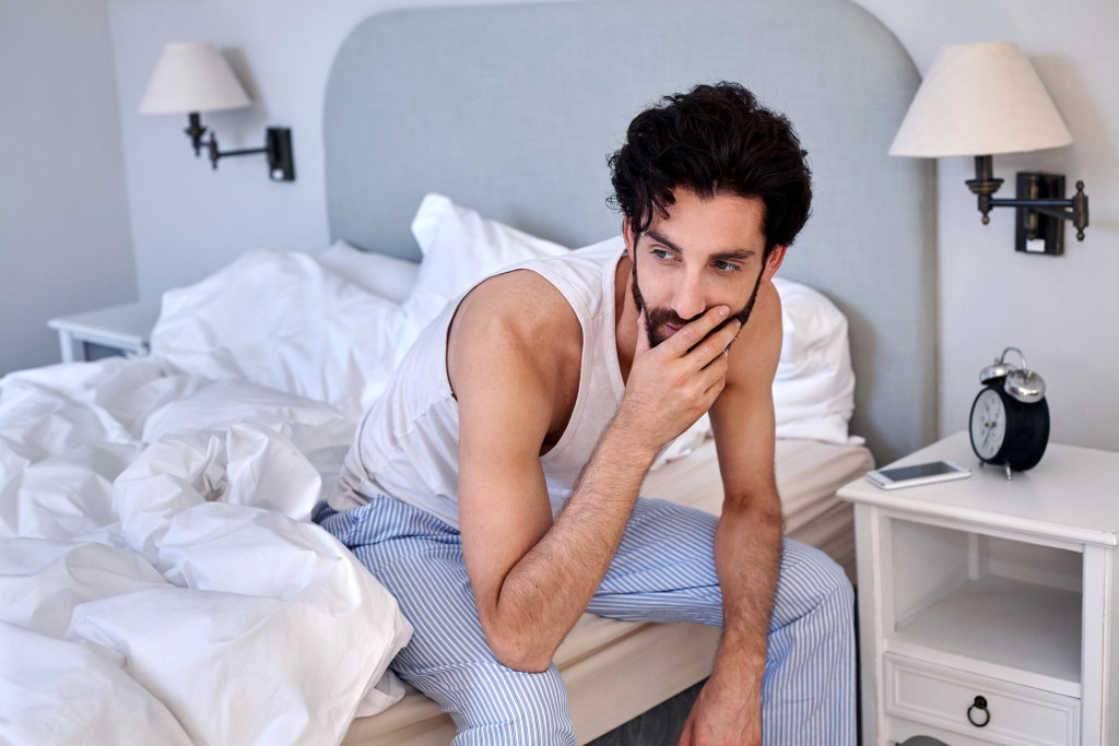 man with beard sitting on bed at home