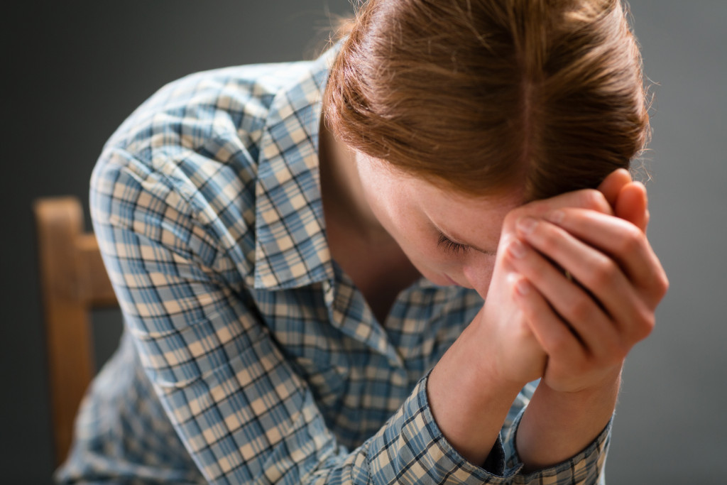 Closeup portrait of a young woman spending time in prayer on a wooden chair.