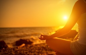 hand of woman meditating in a yoga pose on beach at sunset