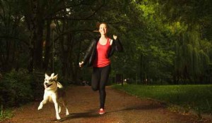 Teenage girl running in park with dog