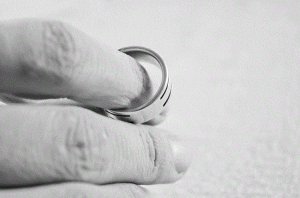 Person holding wedding ring on index finger