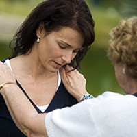 Woman consoling another woman struggling with grief