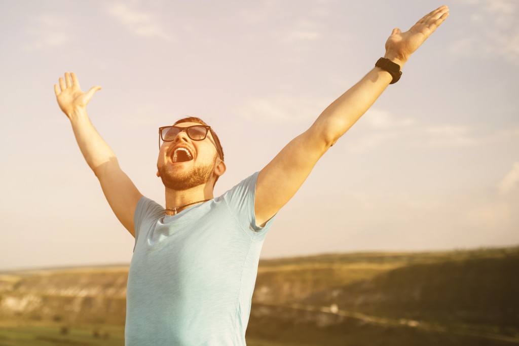 man yelling in joy with arms in air