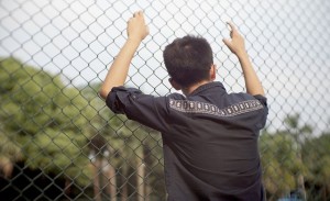 guy leaning on chain link fence thinking about his Sobriety