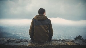 Man sitting on edge of lookout over a vlley