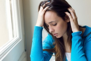 Portrait of depressed young woman sitting at home.