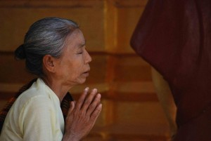 Older Indian woman kneeling and praying 