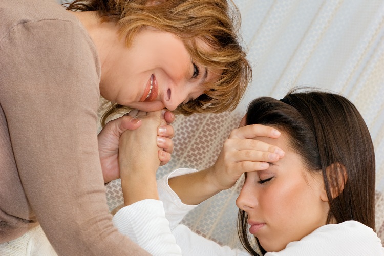 Mature woman consoling her young daughter in the living room.