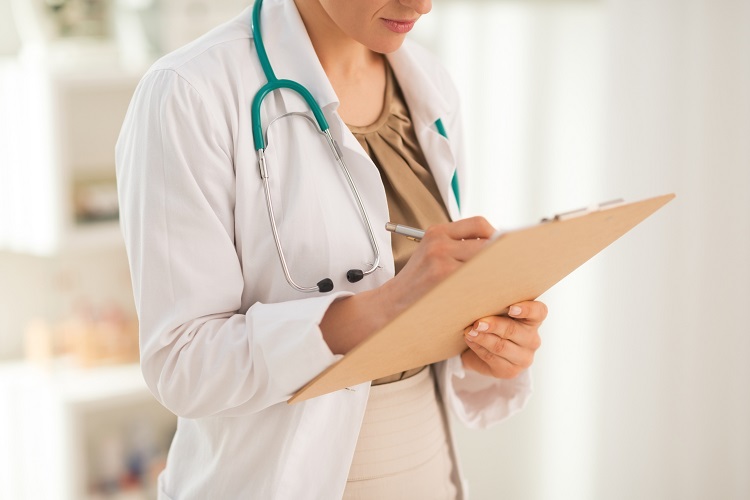 Medical doctor reviewing patients health records on her clipboard