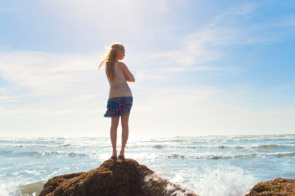 girl on rock facing the sea