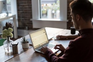 Guy working on computer at coffee house