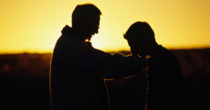 Man Praying Over Teenager about Binge-Drinking and Long-Term Anxiety