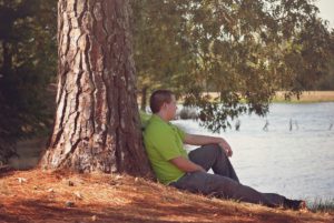 Teenager leaning by tree