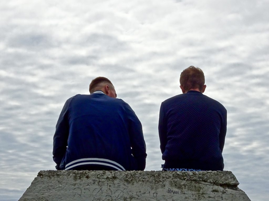 Men sitting on a rock working on a 12-Step recovery Program