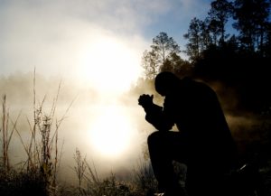 Man praying by the lake