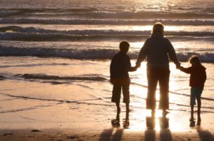 Mother walking with her kids on the beach because husband has an addiction