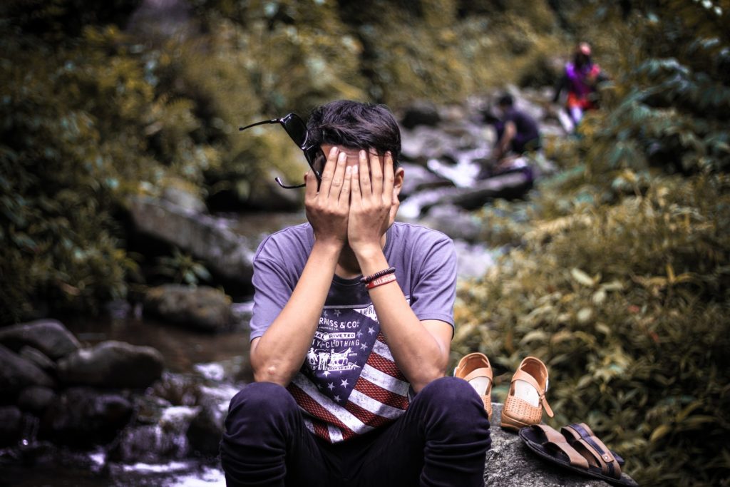 Man sitting by a river sad about the stigma of addiction