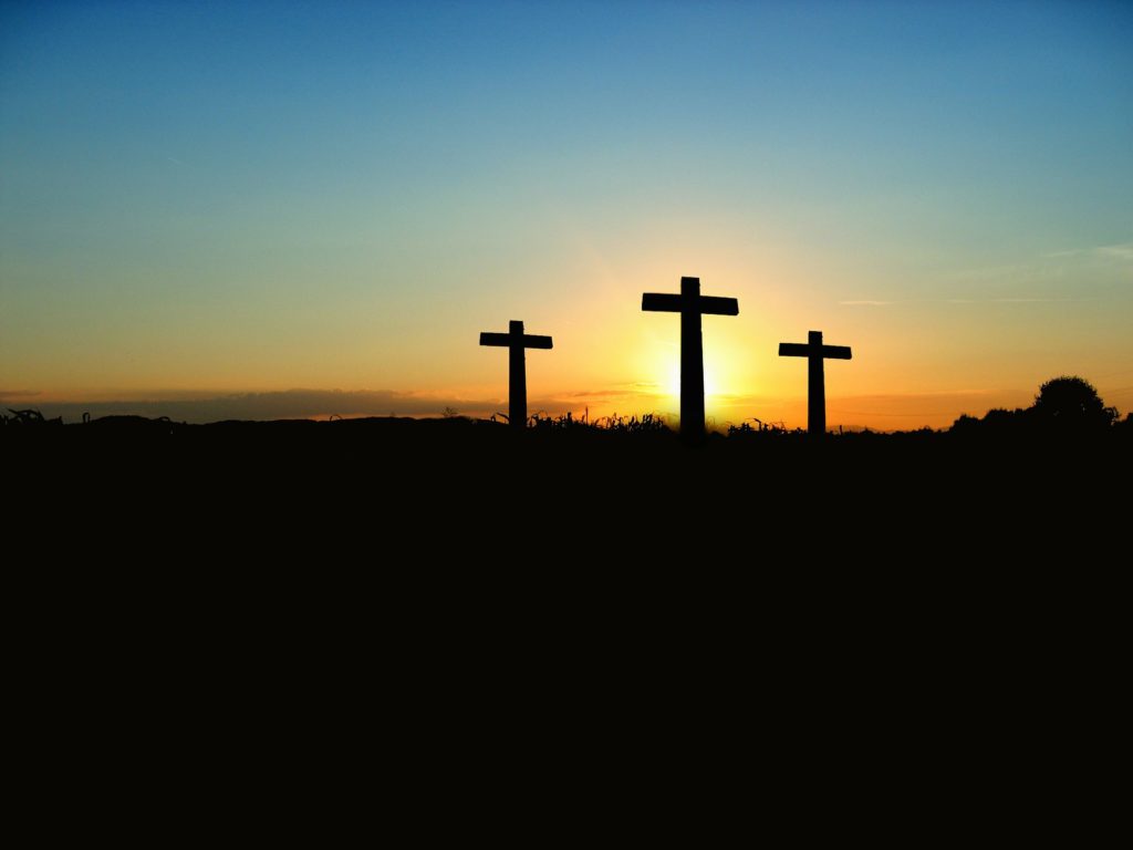 Three crosses with sunset behind it