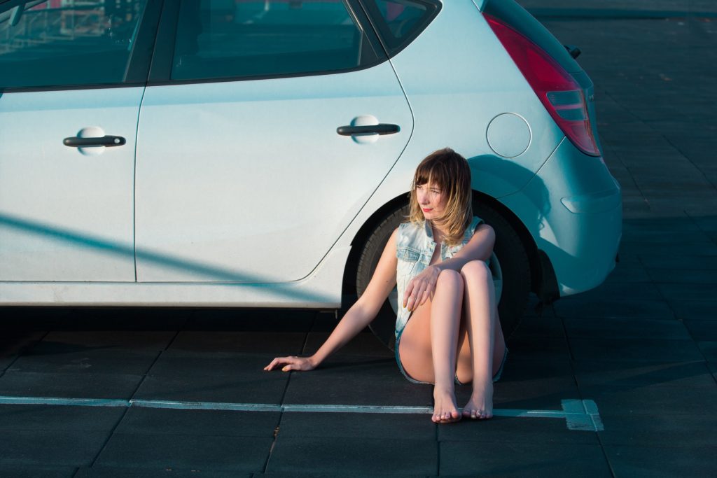 Woman sitting next to her car