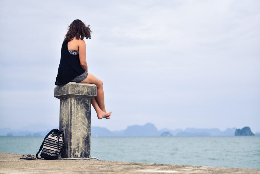 Woman sitting on pillar at the beach