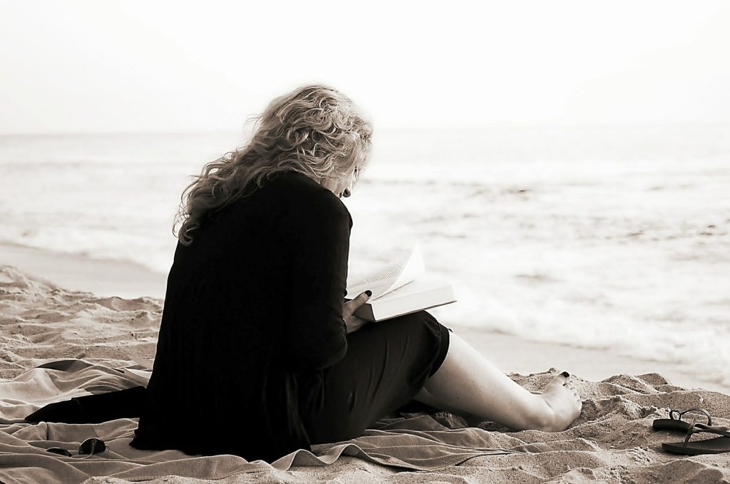 Lady sitting on the beach reading a book